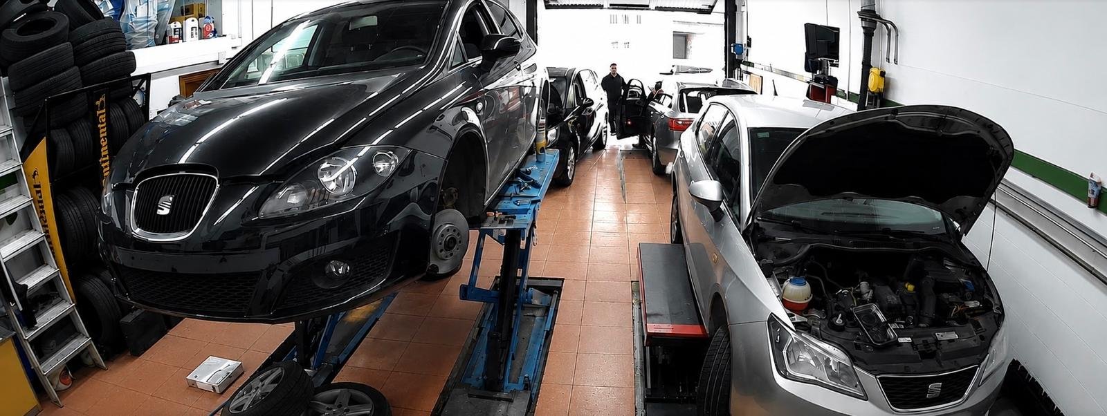 Neumáticos apilados y vehículo elevado en el taller de Talleres Ondiz.