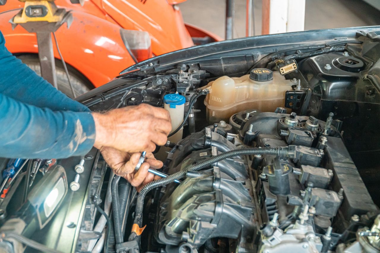Mechanics hands repairing a car engine, showing technical precision in an automotive garage.